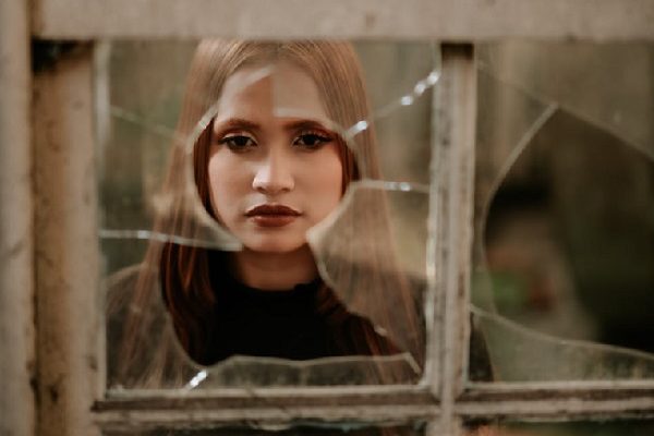 girl looking through broken window